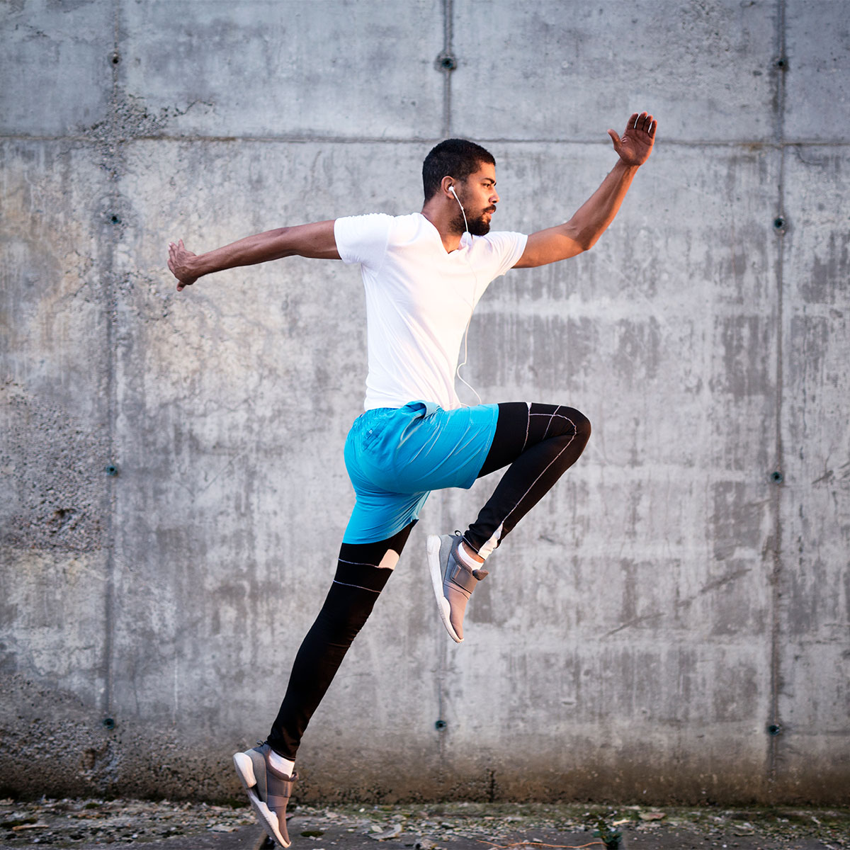 shot-young-sporty-athlete-jump-against-concrete-wall-background-square
