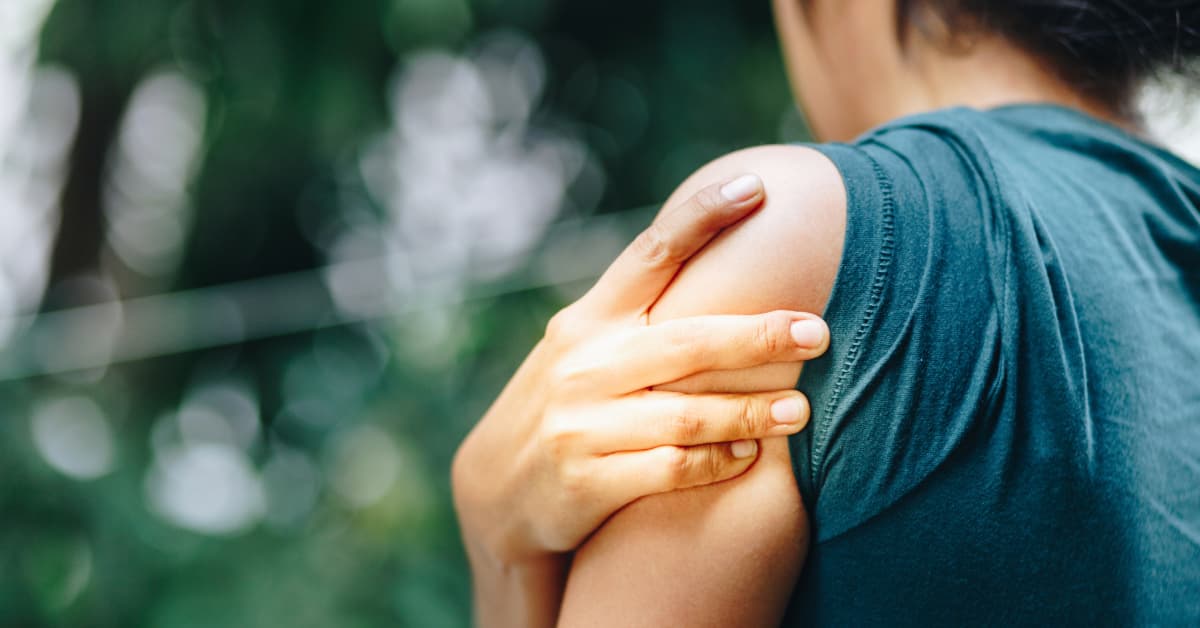 Woman outside holding shoulder due to rotator cuff pain 